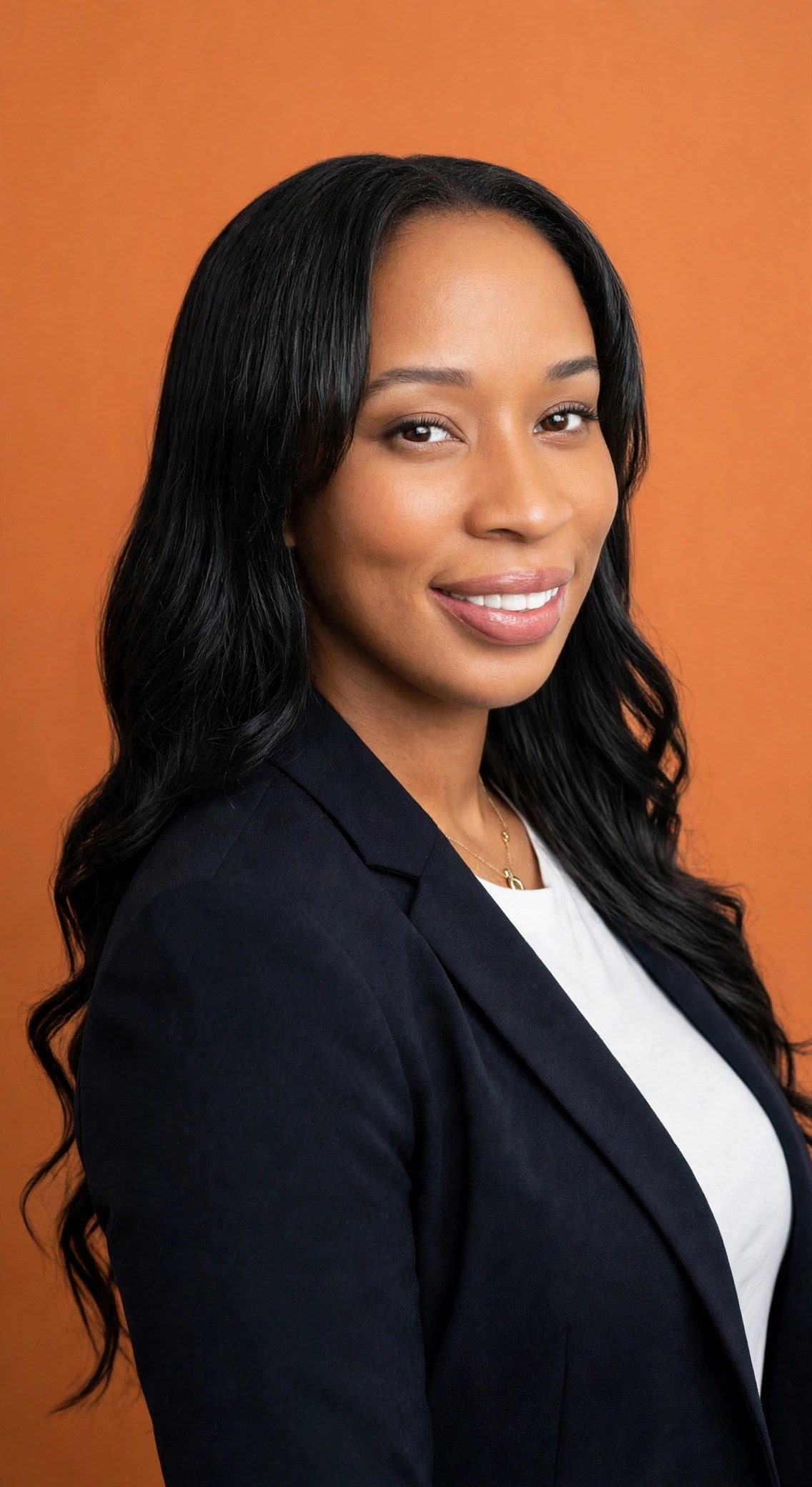 Portrait of Brittnee Crowell in a navy blazer against an orange background